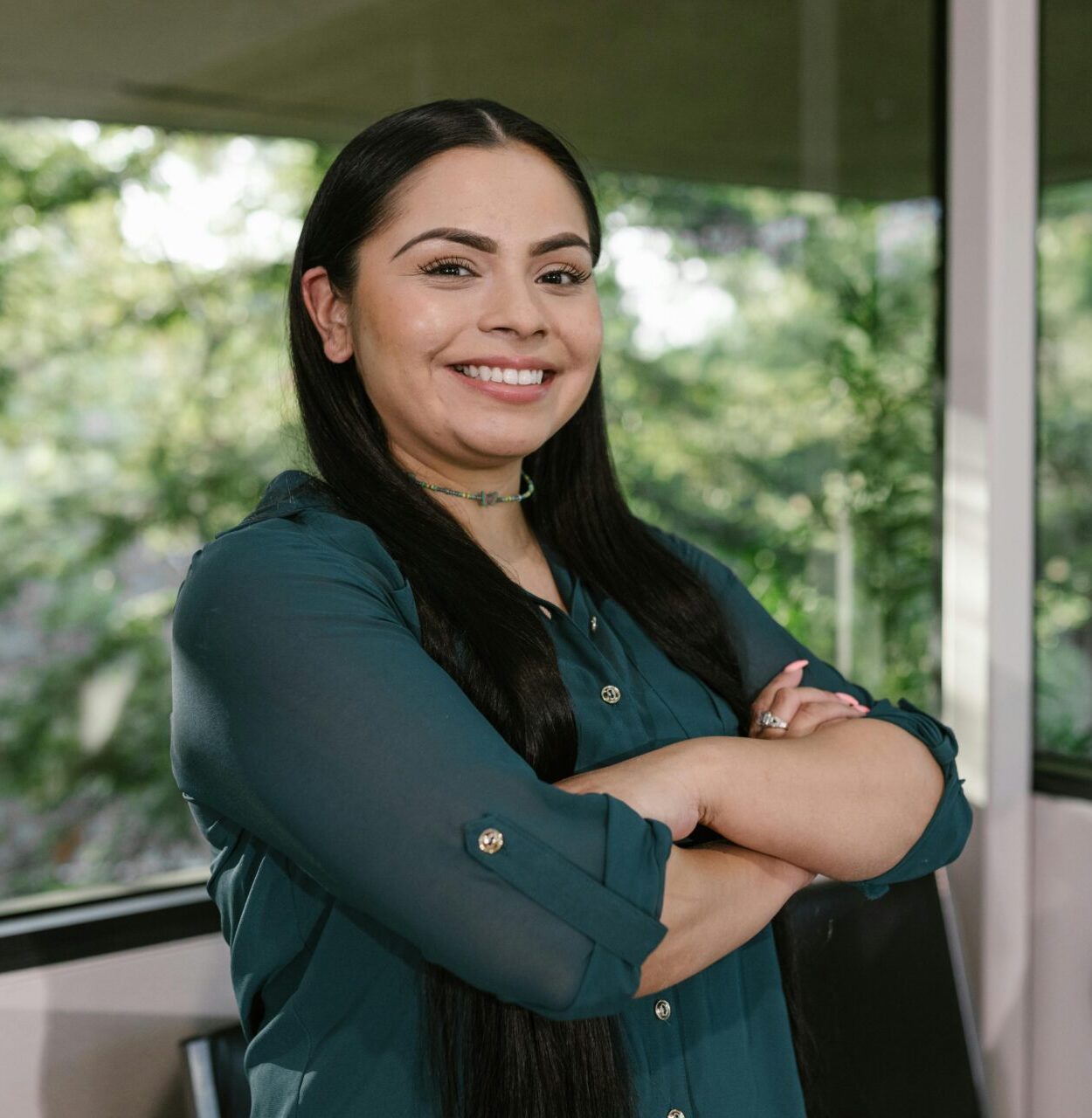 Portrait of a confident businesswoman standing with arms crossed in modern office space.